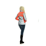 A woman wearing a reflective orange and silver equisafety mercury lightweight reflective riding coat with side zippers