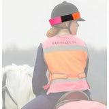 Equisafety equestrian hatband with pink and orange reflective safety vest worn over dark clothes for horses safety