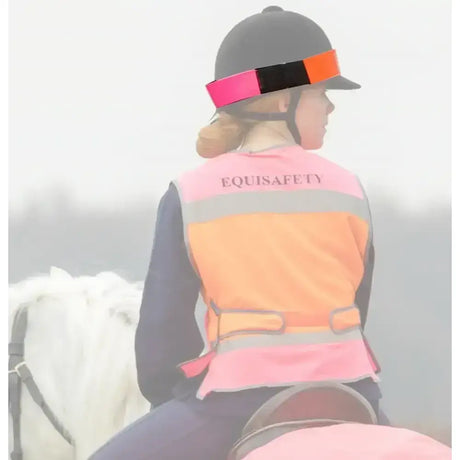 Equisafety equestrian hatband with pink and orange reflective safety vest worn over dark clothes for horses safety