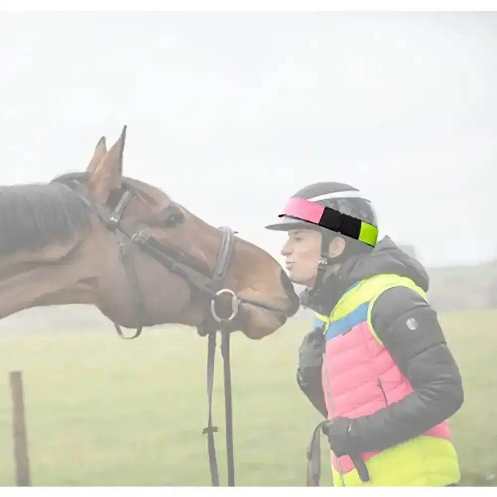 A black racing helmet with a neon green pink and black equisafety multi coloured hatband for equestrian use