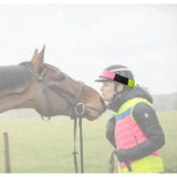 A black racing helmet with a neon green pink and black equisafety multi coloured hatband for equestrian use