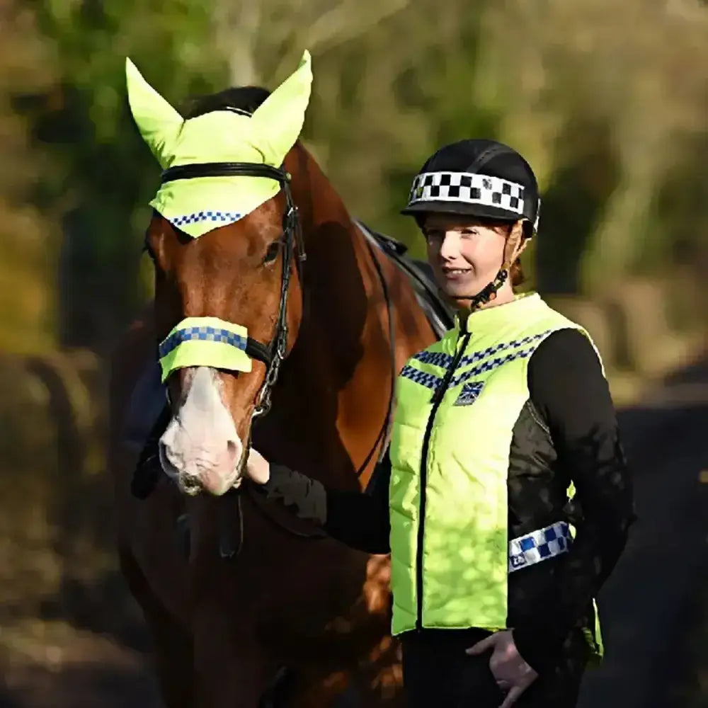 A woman and horse wearing bright neon yellow equisafety polite hat and reflective polite hat band for safety visibility