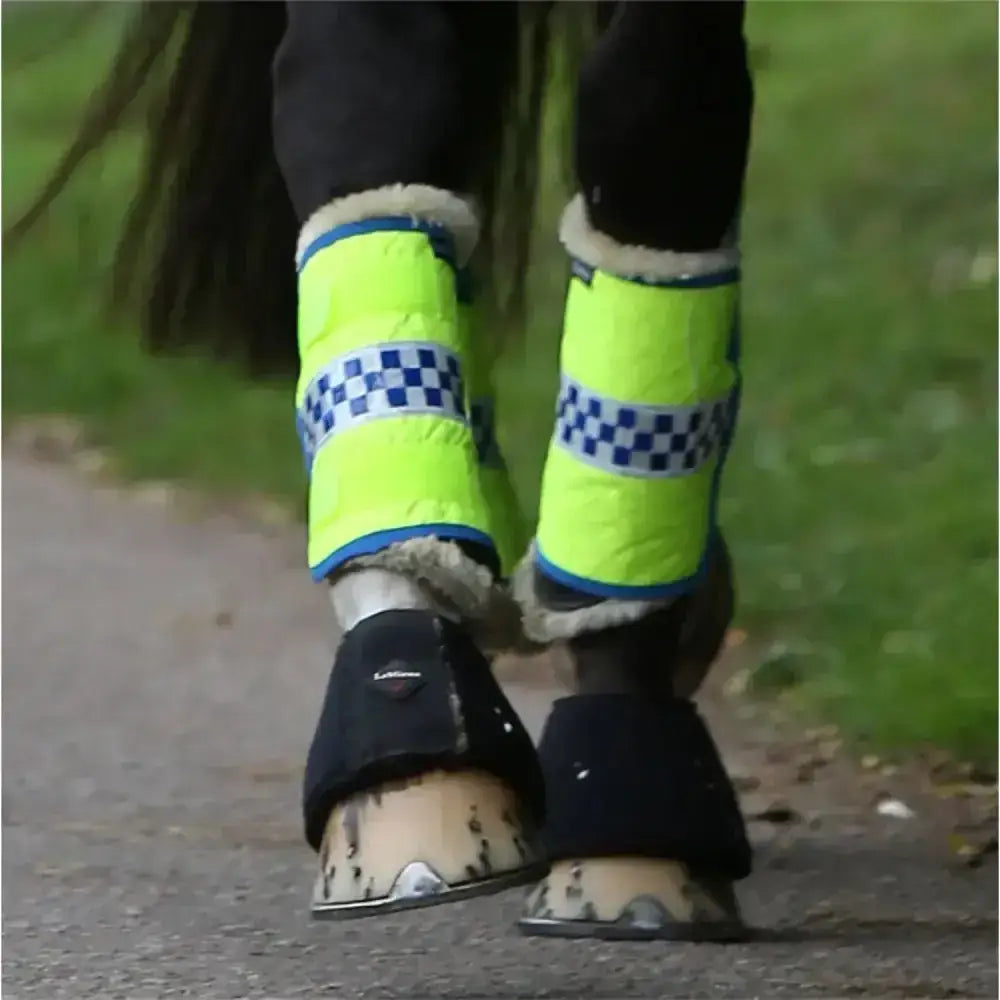Bright neon yellow equisafety polite vis boot wraps with blue white checkered stripes and soft fleece trim for brushing boots