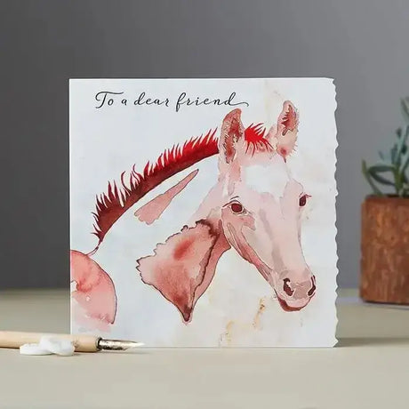 A fanciful dolomite card featuring a white horse with red mane on textured paper individually cello wrapped with outer gloss varnish