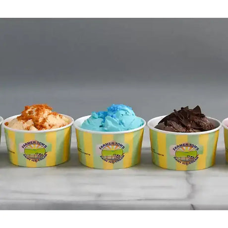 Yellow and green striped paper cups filled with different farmer toms ice cream flavors including clotted cream vanilla small tubs