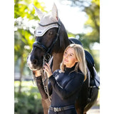 Black horse wearing a white and gray mesh finesse fly hood stone with black leather straps for fly protection