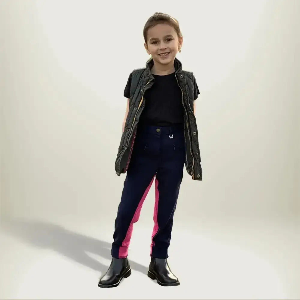 A child wearing gallop children’s two tone jodhpurs with eye catching contrast pink side panels and shiny black boots