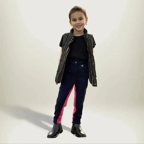 A child wearing gallop children’s two tone jodhpurs with eye catching contrast pink side panels and shiny black boots