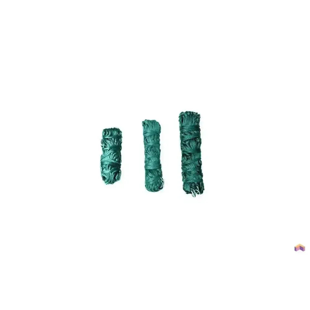 Three rolled sage bundles wrapped in dark green twine with leaf patterns next to a gallop large haynet with length tie string