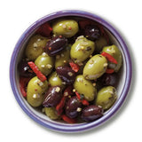A bowl of garlic peppers and mustard seed pitted olives with green olives red pepper strips and chopped garlic