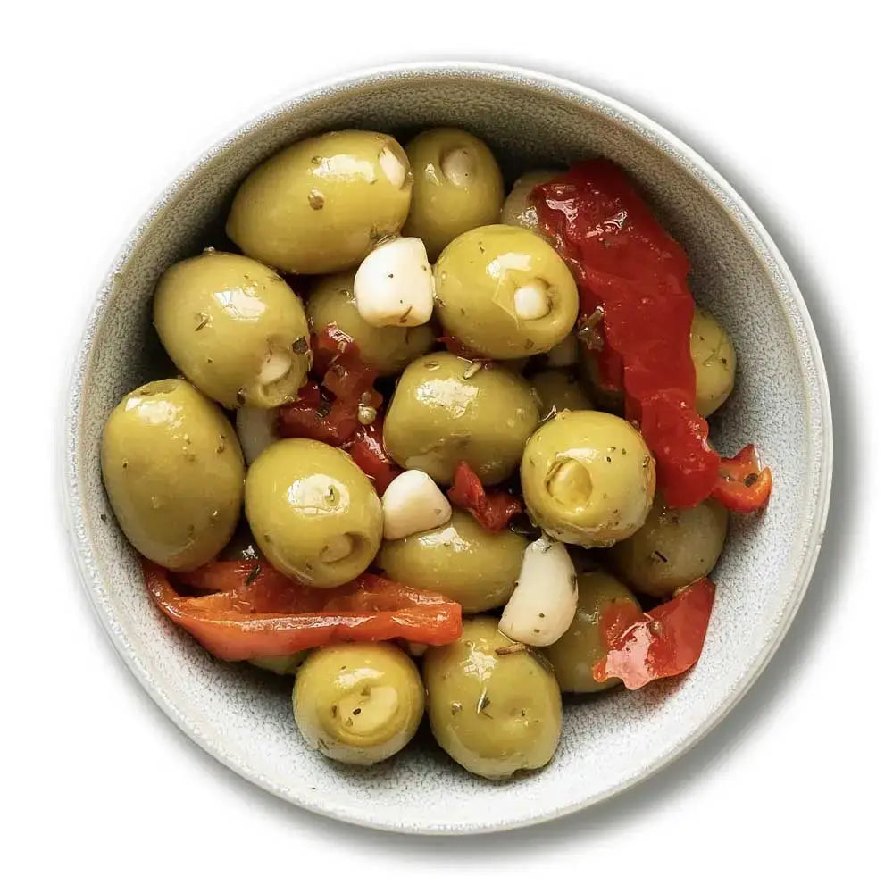 A speckled gray ceramic bowl of garlic stuffed green olives with red peppers and garlic cloves for snacking