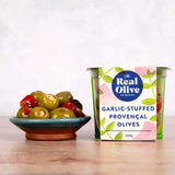 A container of garlic stuffed green provençal olives from the real olive company with colorful floral label