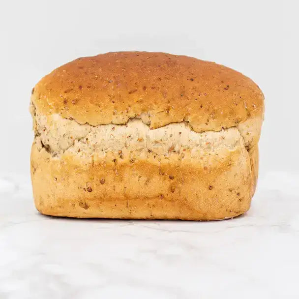 Golden brown round granary farmhouse loaf with rustic cracked crust and seeds baked into the dough