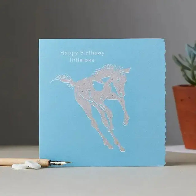 Happy birthday card boy foal with light blue natural fleck background and silver foil horse silhouette design