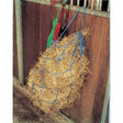 Blue woven large holed haynet from harlequin haynets large filled with golden straw hanging on wooden stall gate