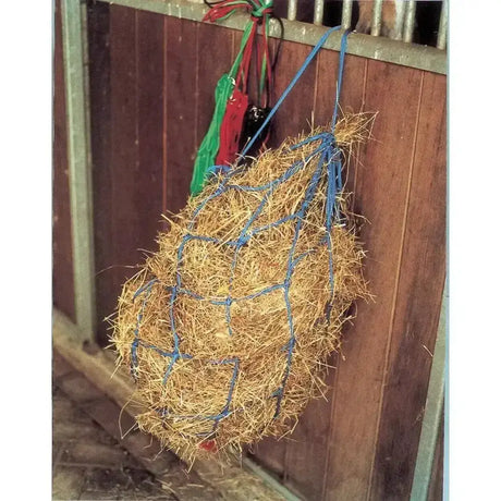 Blue woven large holed haynet from harlequin haynets large filled with golden straw hanging on wooden stall gate