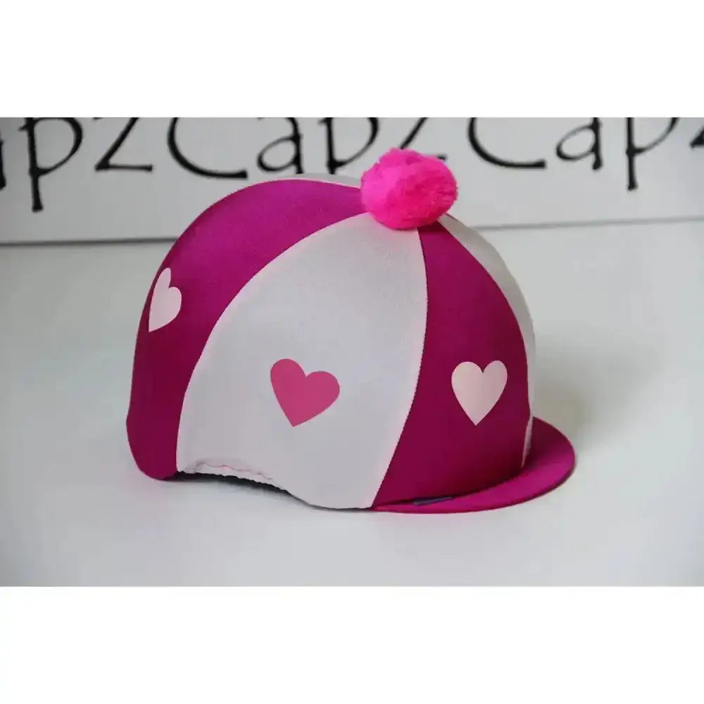 A vibrant pink and white striped pom poms hat silks two colour riding hat cover with heart cutouts and fluffy pom pom