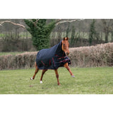A dark navy rhinegold aspen 350g heavy weight combo turnout rug with red trim snug on a chestnut horse