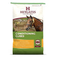 A brown horse wearing a halter stands in a rural area promoting heygates horse and pony conditioning cubes