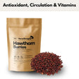 A 1kg matte gold pouch of horse straights direct hawthorn whole berries next to a pile of deep red dried berries