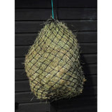 A hungry horace greddy feeder haynet in black mesh filled with green and yellow straw hanging by a teal rope