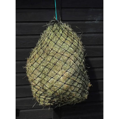A hungry horace greddy feeder haynet in black mesh filled with green and yellow straw hanging by a teal rope