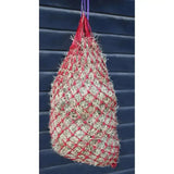 Red and beige woven haynet hanging from a purple strap for hungry horace horace greedy feeder use