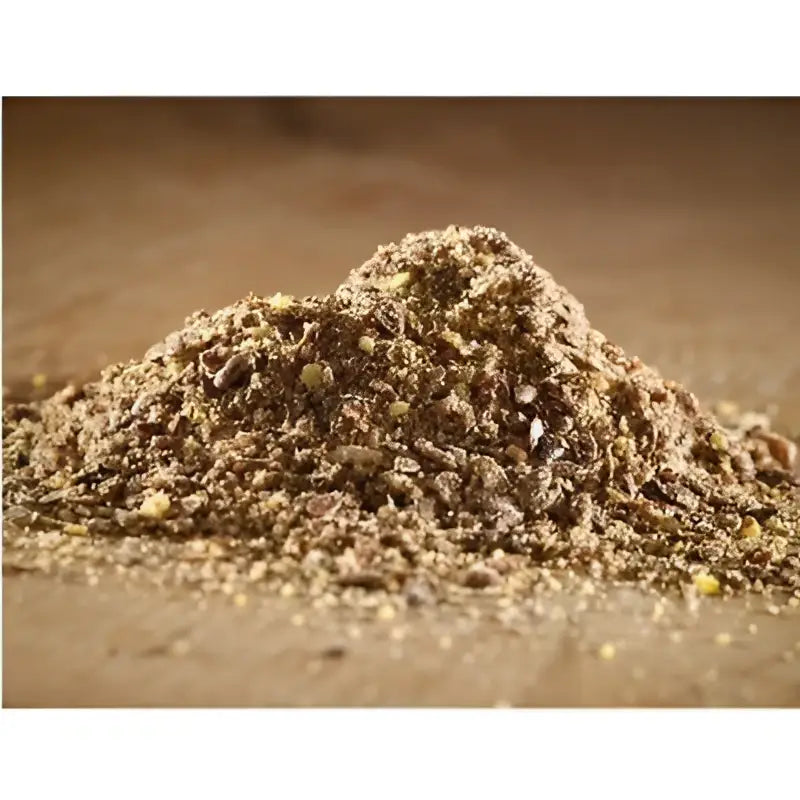 A mound of brown granular cooked linseed meal with specks used as fish bait from hutton mill
