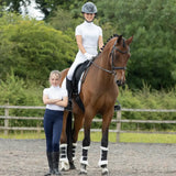 A sleek chestnut horse stands calmly in an arena showcasing equestrian children’s roka regal riding tights