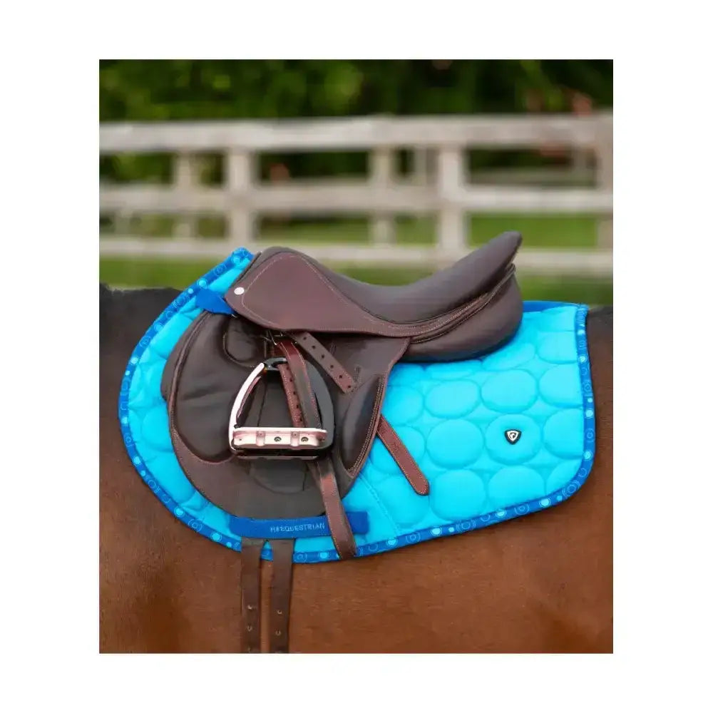 Bright blue quilted dynamizs ecliptic close contact saddle pad with subtle pattern brown leather trim and brand logo