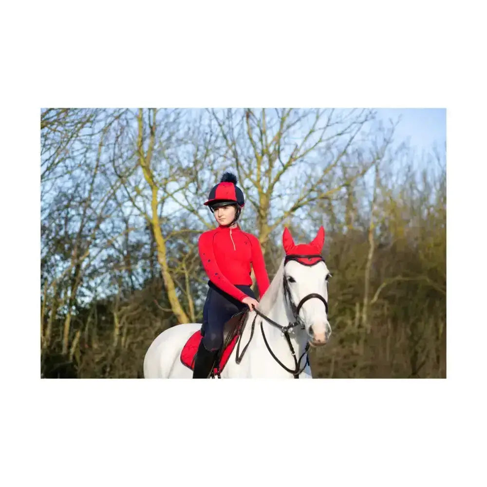 Red equestrian helmet with black brim and blue pom-pom featuring hy equestrian dynamizs ecliptic fly veil close-knit crochet design