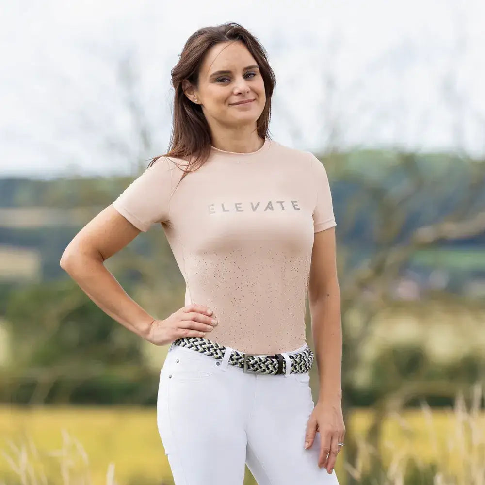 A soft blush-colored hy equestrian elevate allure t-shirt with short sleeves and metallic elevate print on the chest