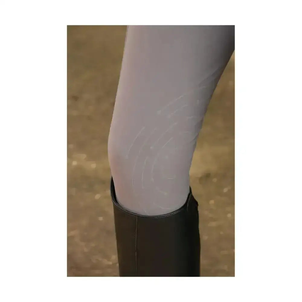 A pair of light gray sheer hy equestrian glacial softshell riding tights worn with a black boot showing brushed fleece lining
