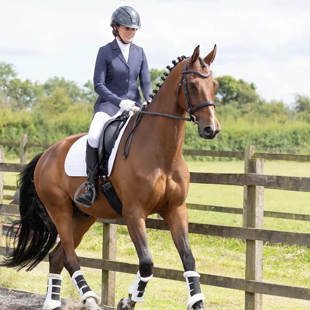 A sleek chestnut horse with black mane wearing white leg wraps and a dark bridle showcasing the roka regal show jacket