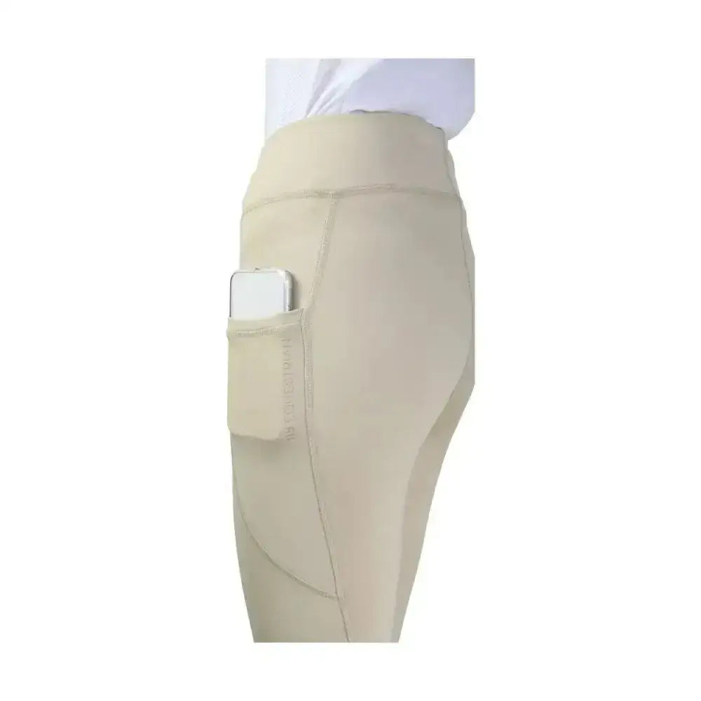 Beige high-waisted hy equestrian selah competition riding tights with a side pocket holding a smartphone