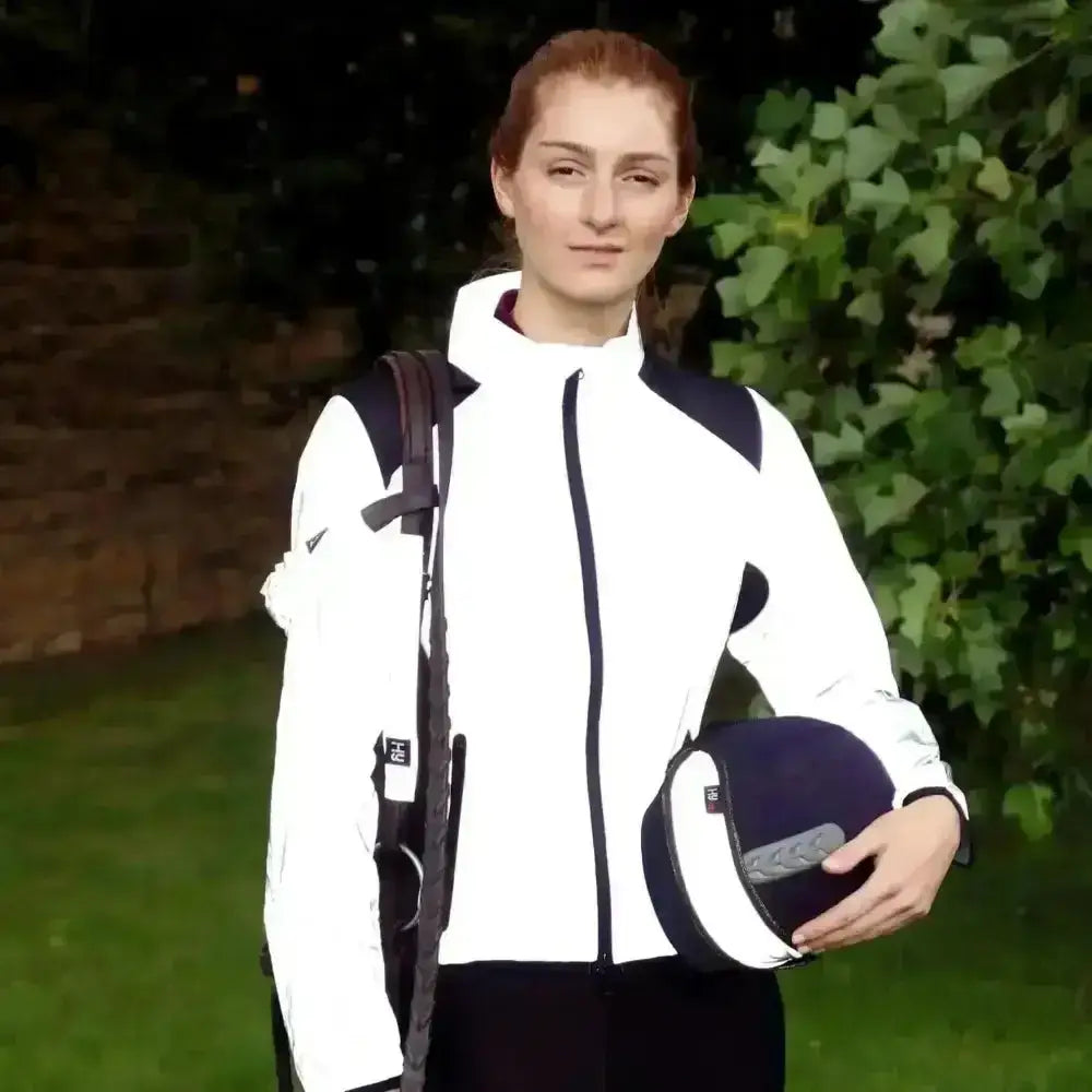White and navy equestrian helmet with black trim paired with hy equestrian silva flash reflective jacket