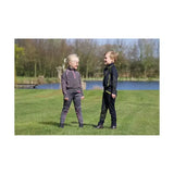 Two kids wearing matching funky base layer equestrian stella star patterned outfits standing in grassy field