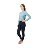 Light blue long-sleeved hy equestrian synergy base layer with high collar and navy perforated riding pants for equestrian athletes