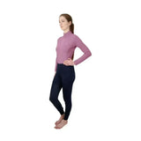 A woman wears a fitted lavender long-sleeve Hy Equestrian synergy base layer shirt with a high collar and zipper front