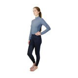 A woman wearing a light blue hy equestrian synergy base long sleeve top and navy synergy base layer leggings