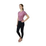 A woman wearing black Hy Equestrian synergy riding tights that allow unrestricted movement and a soft lavender top