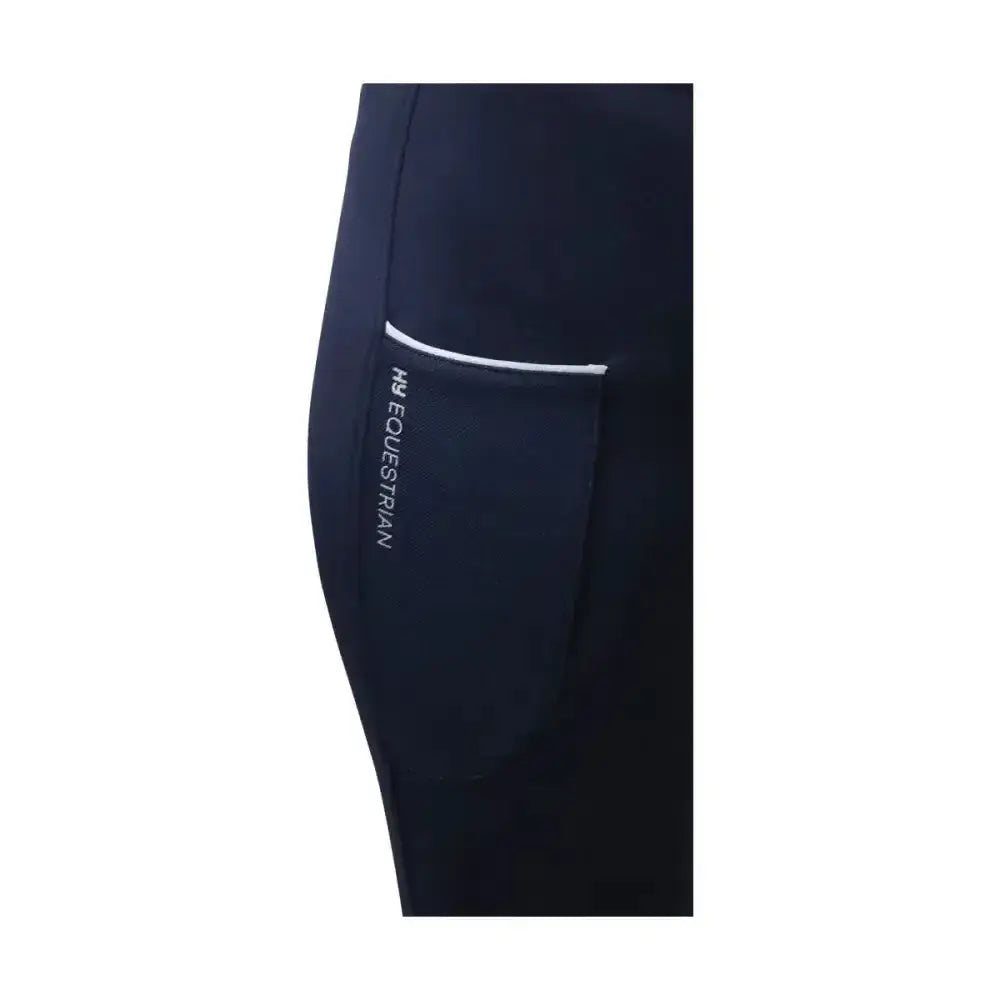 Navy blue Hy Equestrian synergy riding tights with white-trimmed side pocket and silver h&g equestrian branding allow unrestricted movement