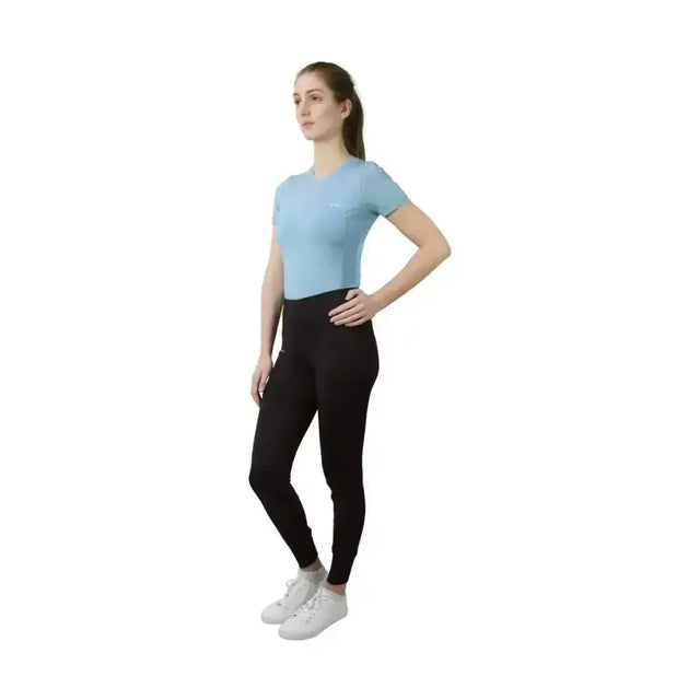 A woman wearing a hy equestrian synergy t-shirt aqua in light blue with short sleeves and black leggings