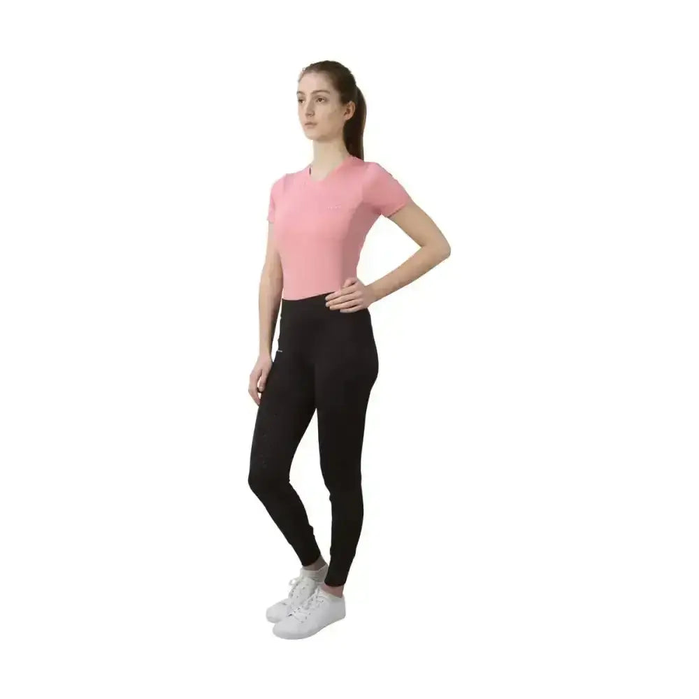 A woman wearing the hy equestrian synergy t-shirt rose in pink made from super soft material and black leggings