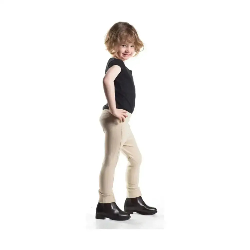 Child wearing beige equestrian zeddy tots jodhpurs with a black top and ankle boots showcasing pull-on tots jodhpur style