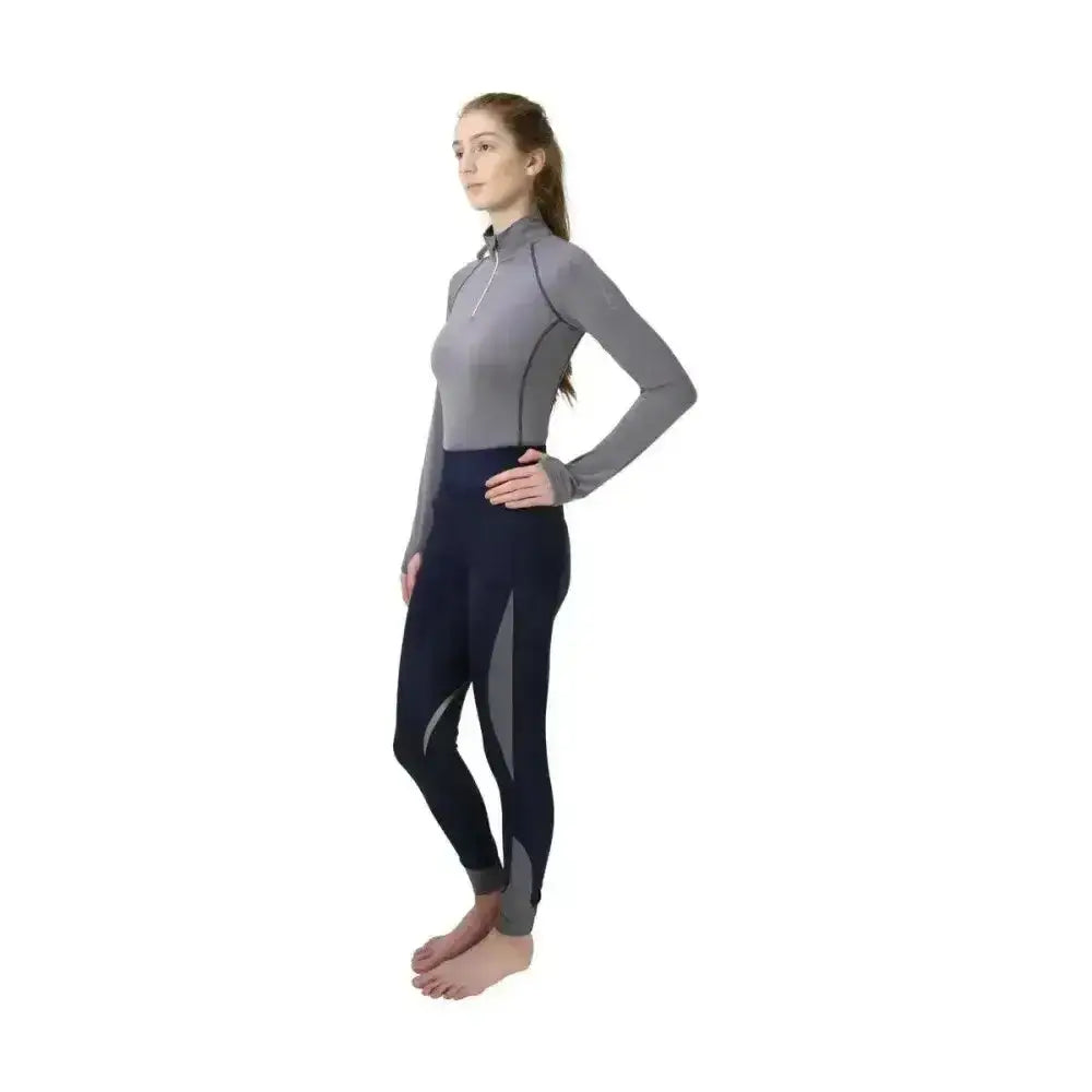 A woman wearing hy sport active base layer with gray soft breathable fabric top and close fit navy leggings with gray panels