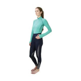 A woman wearing a teal hy sport active base layer with black gray panels made of soft breathable fabric close fit base