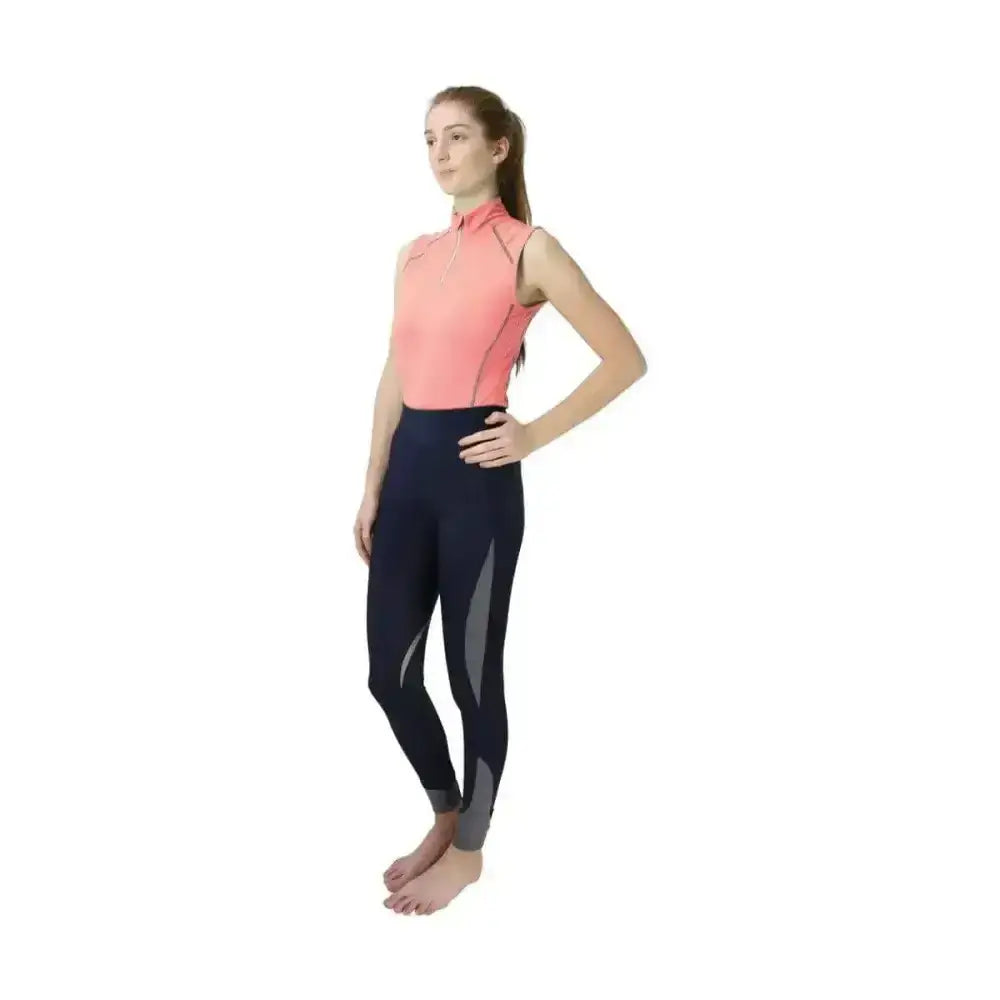 A woman in a coral hy sport active sleeveless top paired with navy blue leggings from the sport active collection base layers