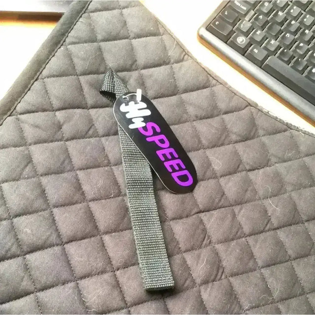 Black and purple the speed tag attached to gray woven strap on hyspeed dressage cloth black pony