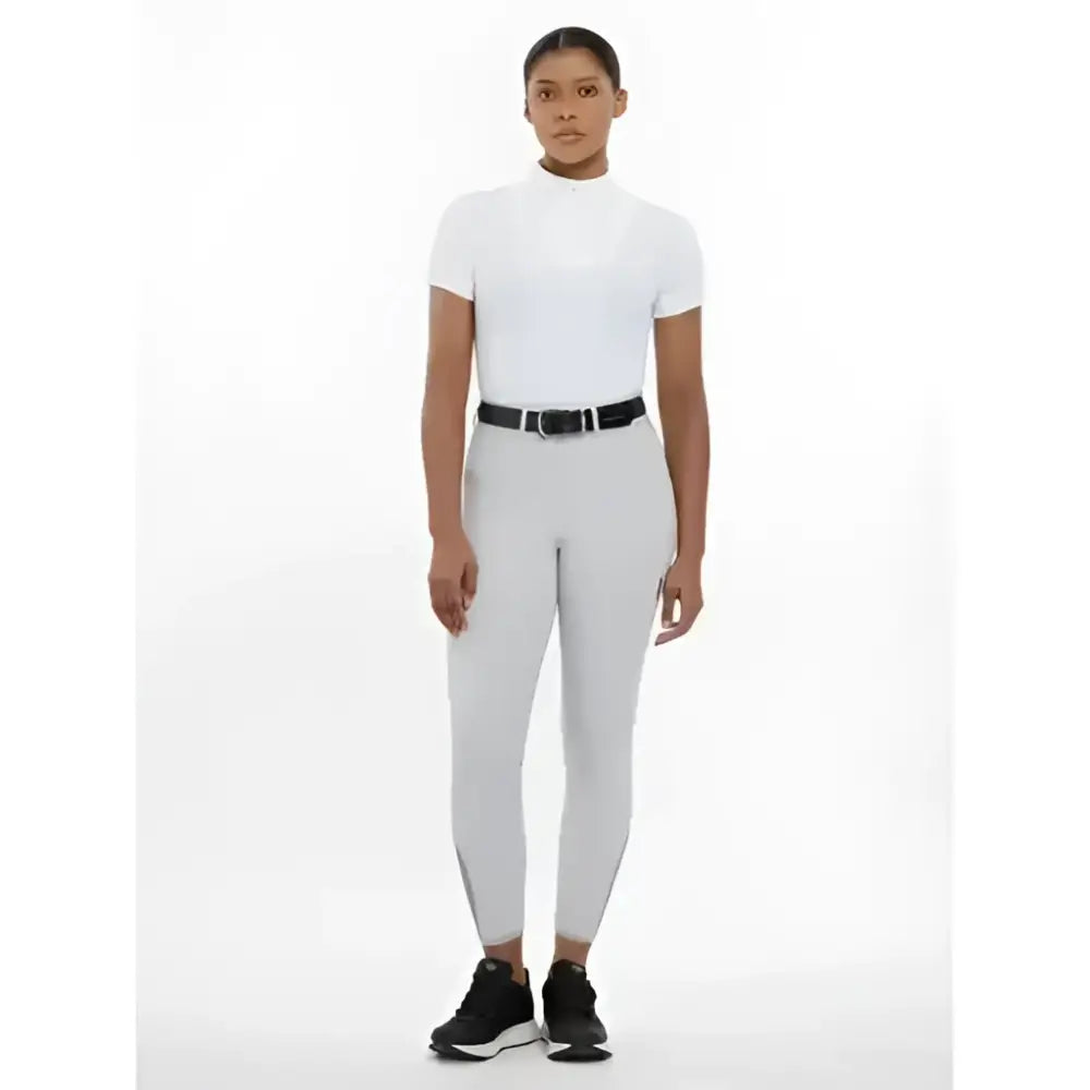 Woman wearing imogen knee grip breeches light grey with a white high neck short sleeve top and black belt